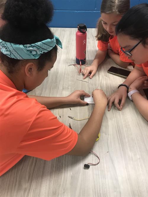 Three girls put breadboard together while collaborating on circuits 